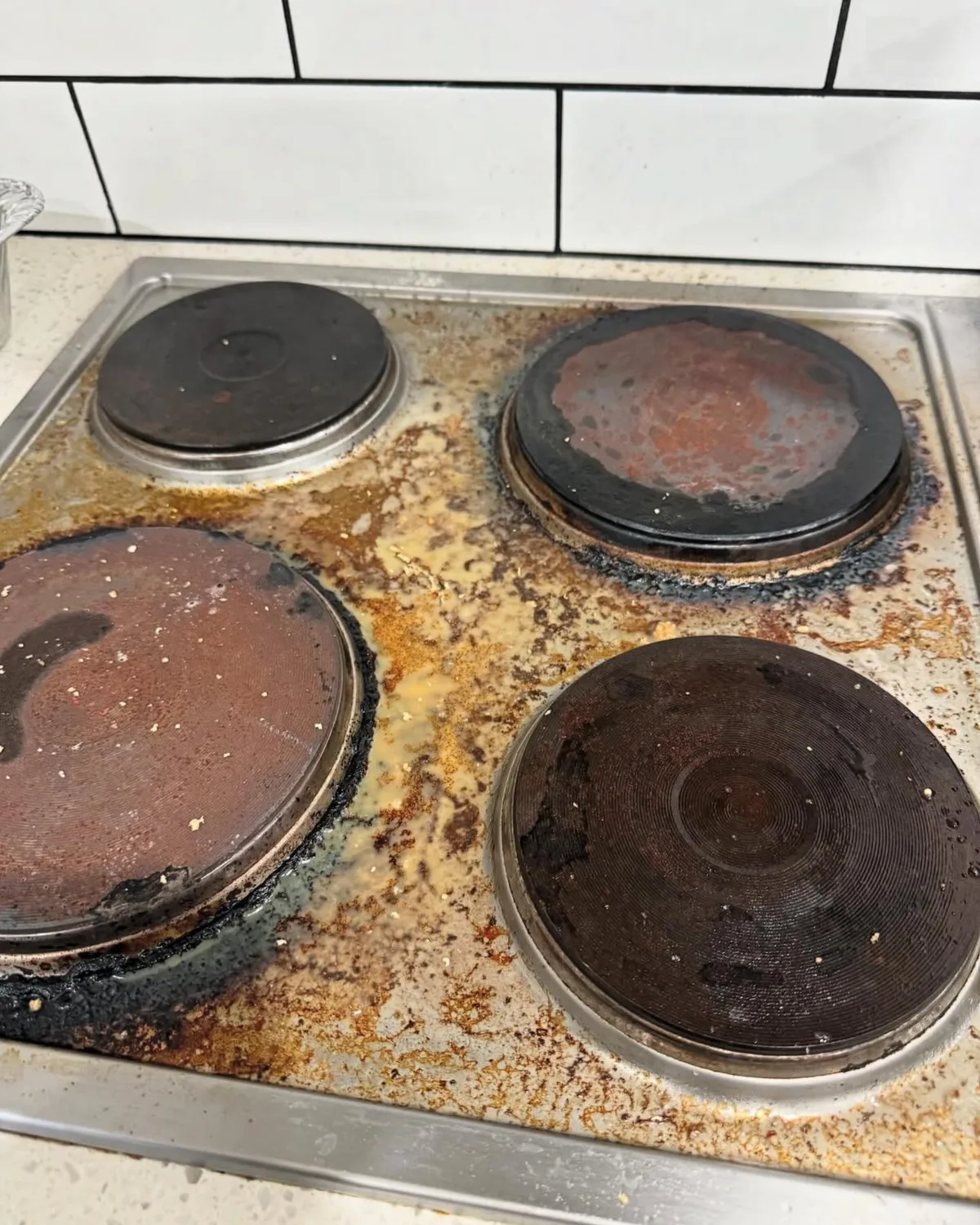 Real customer kitchen stovetop covered in built-up grease and grime before an Oz SpotNest clean